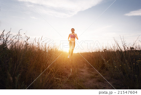 Young sporty girl running on a rural road. Sunset Young sporty girl running on a rural road. Sunset 21547604