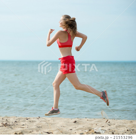 Young lady running at the sunny summer sand beach 21553296