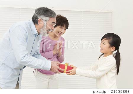 プレゼントを渡す祖父母と孫 プレゼント 祖父母 孫 シニア 女の子の写真素材