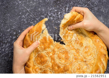 Hands breaking bread on grey rustic background 21562951