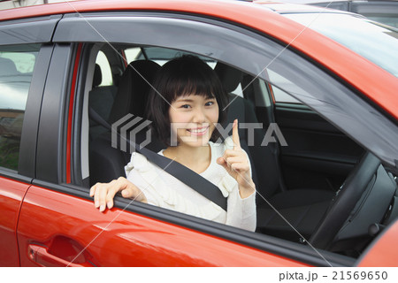 運転席に乗り笑顔で指差しをする若い女性 運転席に乗り笑顔で指差しをする若い女性 21569650