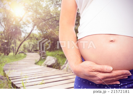 Composite image of pregnant woman holding baby shoes over bump 21572181