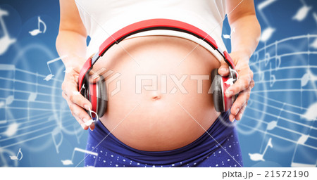 Composite image of pregnant woman holding earphones over bump 21572190