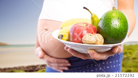 Composite image of pregnant woman showing fruit and veg  21572292