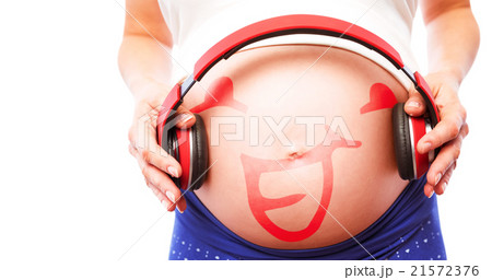 Composite image of pregnant woman holding earphones over bump Composite image of pregnant woman holding earphones over bump 21572376