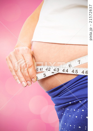 Composite image of pregnant woman measuring her bump Composite image of pregnant woman measuring her bump 21572637