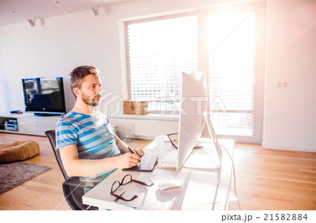 Man sitting at desk working from home on computer Man sitting at desk working from home on computer 21582884