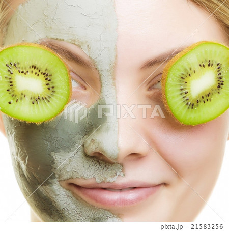 Woman in clay facial mask covering eyes with kiwi Woman in clay facial mask covering eyes with kiwi 21583256