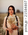 Young girl with long dark hair holding white flowers at the spring field. 21584807