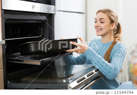 girl putting baking tray in kitchen oven girl putting baking tray in kitchen oven 21594704