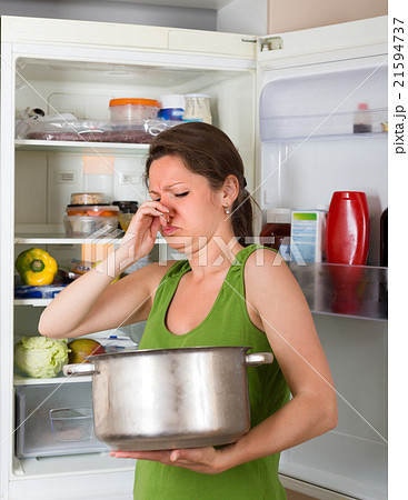 Woman holding foul food near frige. Woman holding foul food near frige. 21594737