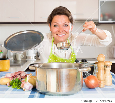 Happy housewife cooking meat and potatoes Happy housewife cooking meat and potatoes 21594793