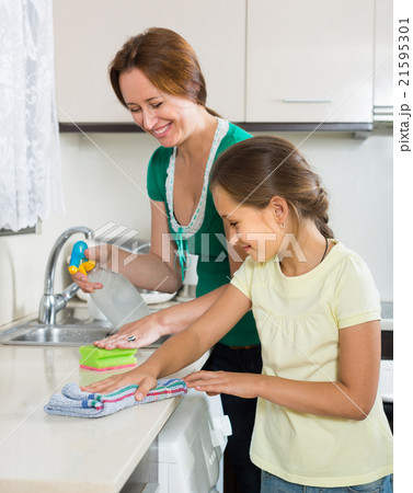 Little girl helping mother at kitchen Little girl helping mother at kitchen 21595301