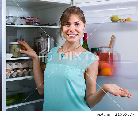 adult girl arranging space of fridge shelves indoors adult girl arranging space of fridge shelves indoors 21595677