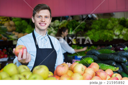 Young smiling male dealer lays out the apples Young smiling male dealer lays out the apples 21595892