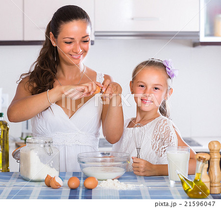 Happy girl helping mother at kitchen. Happy girl helping mother at kitchen. 21596047