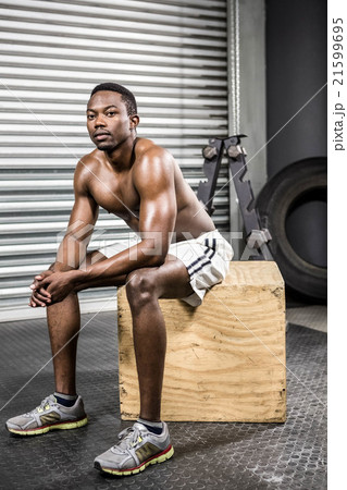Shirtless man sitting on wooden block 21599695