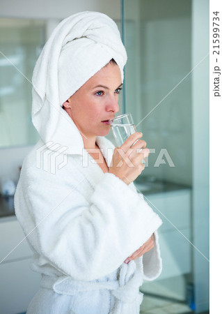 woman wearing a dressing gown drinking a glass of water woman wearing a dressing gown drinking a glass of water 21599734