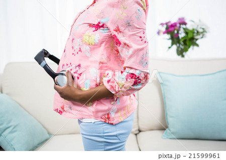 Pregnant woman holding headphone on belly Pregnant woman holding headphone on belly 21599961