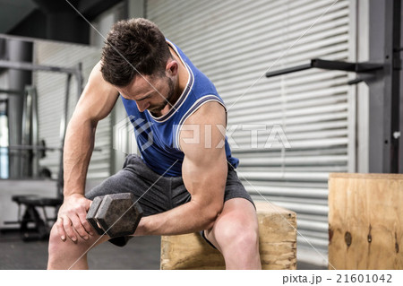 Muscular man lifting dumbbell on wooden block Muscular man lifting dumbbell on wooden block 21601042