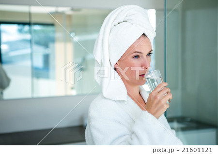woman in a dressing gown drinking a glass of water 21601121