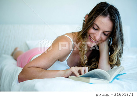 smiling woman reading a book in bed smiling woman reading a book in bed 21601371