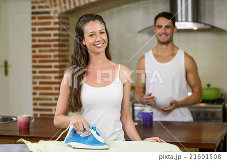 Portrait of woman ironing a shirt in kitchen 21601508