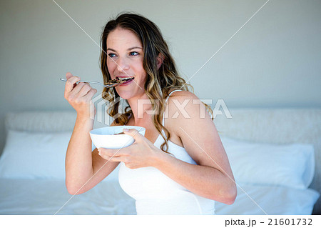 smiling woman eating a bowl of cereal smiling woman eating a bowl of cereal 21601732