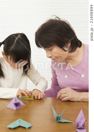 折り紙を折る孫と祖母 女の子 シニア 折り紙の写真素材