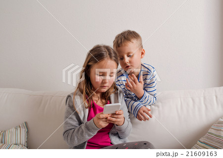 Children at home sitting on sofa, playing with 21609163