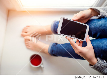 Unrecognizable woman sitting on window sill with Unrecognizable woman sitting on window sill with 21624124