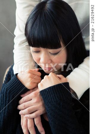 後ろから抱きしめられる女性の写真素材