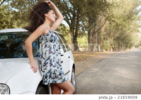 girl stand on country road near auto, big high trees, summer season 21659009