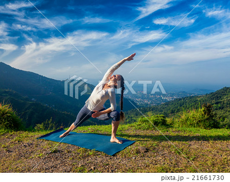 Woman practices yoga asana Utthita Parsvakonasana Woman practices yoga asana Utthita Parsvakonasana 21661730