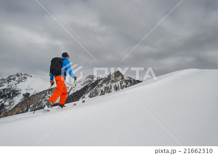 Man with ski mountaineering climb towards the summit 21662310