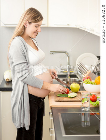 smiling pregnant woman cooking dinner on kitchen smiling pregnant woman cooking dinner on kitchen 21668230