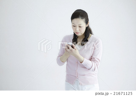自然光白バック40代女性ミドルエイジ　スマホ/メッセージ　不慣れな操作シーン 21671125