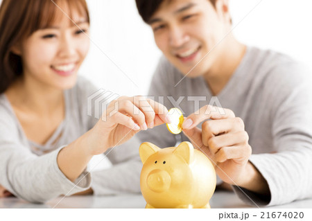 Happy young Couple Inserting Coin In Piggybank 21674020