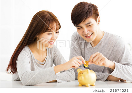 Happy young Couple Inserting Coin In Piggybank 21674021