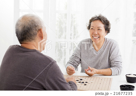 happy asian senior couple playing chess in living room 21677235
