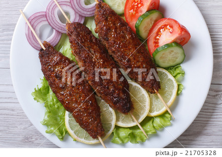 Roasted kebabs on a plate with vegetables top view Roasted kebabs on a plate with vegetables top view 21705328