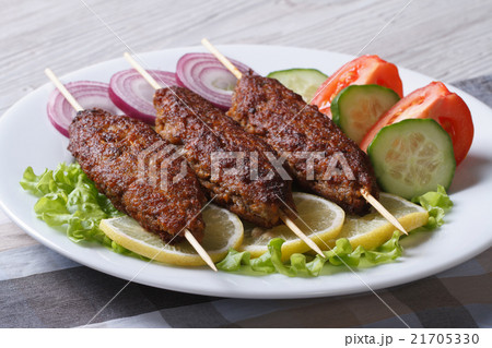 Grilled kebabs on wooden skewers and vegetables Grilled kebabs on wooden skewers and vegetables 21705330