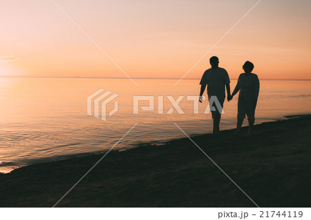 Silhouette of adult couple walks on the seashore Silhouette of adult couple walks on the seashore 21744119