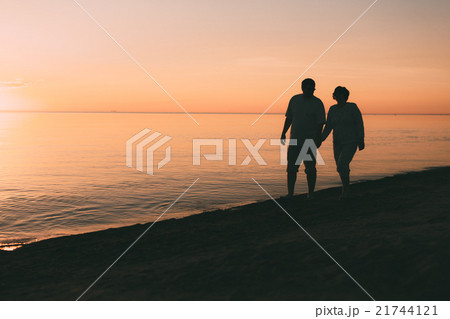 Silhouette of adult couple walks on the seashore Silhouette of adult couple walks on the seashore 21744121