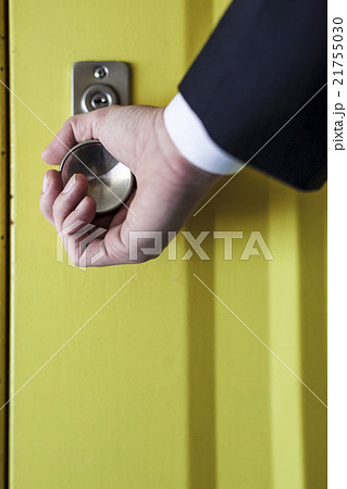 ドアノブを握るビジネスマンの手元の写真素材