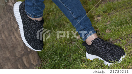 Feet in sneakers in green grass 21789211