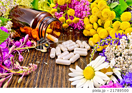 Capsules in brown jar with flowers on board Capsules in brown jar with flowers on board 21789500