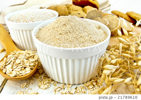 Flour oat in white bowl with flakes on board 21789610