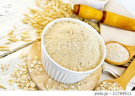 Flour oat in white bowl with flakes on light board 21789611