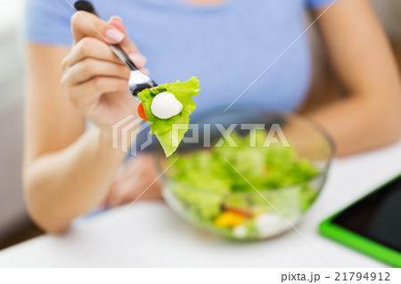 close up of young woman eating salad at home 21794912